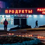 man in black jacket and black pants standing near red and white UNKs store during